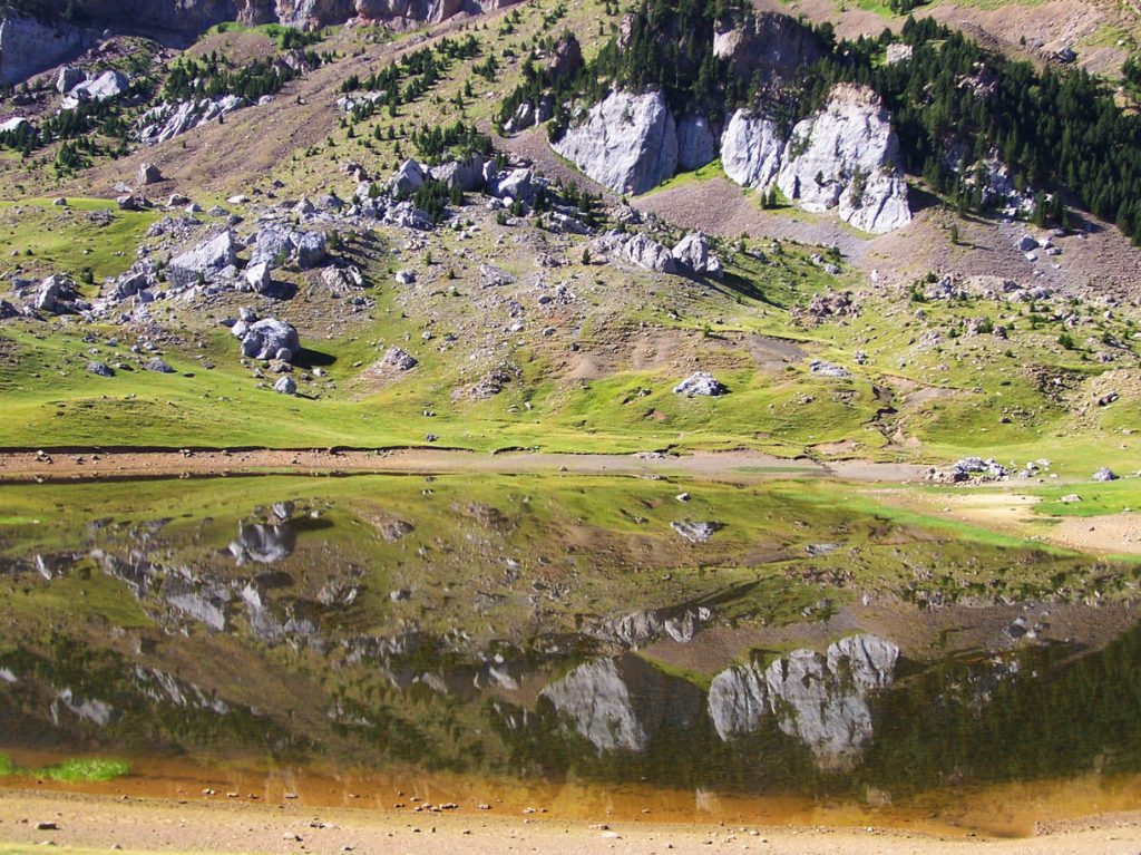 Ibón de Piedrafita con las laderas y roquedos de la sierra de la Partacua