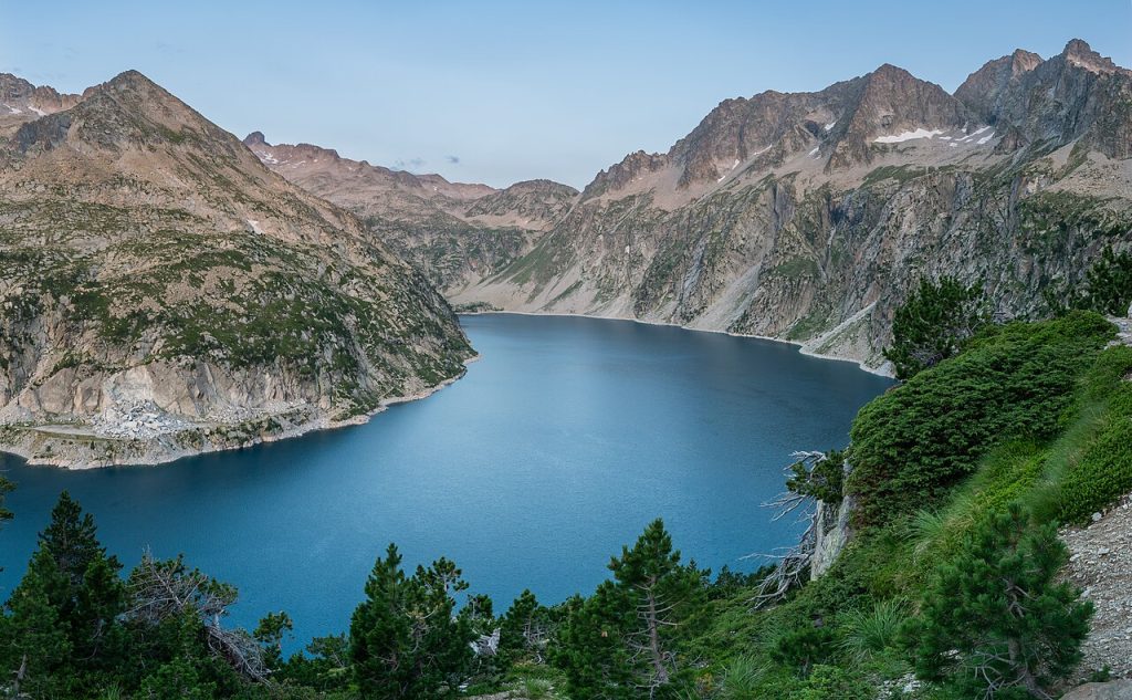 Lago de Cap de Long de aguas azules entre cumbres escarpadas del macizo de Néouvielle
